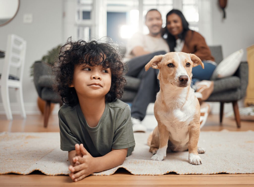 Shot of a little boy bonding with his dog while his parents sit in the background